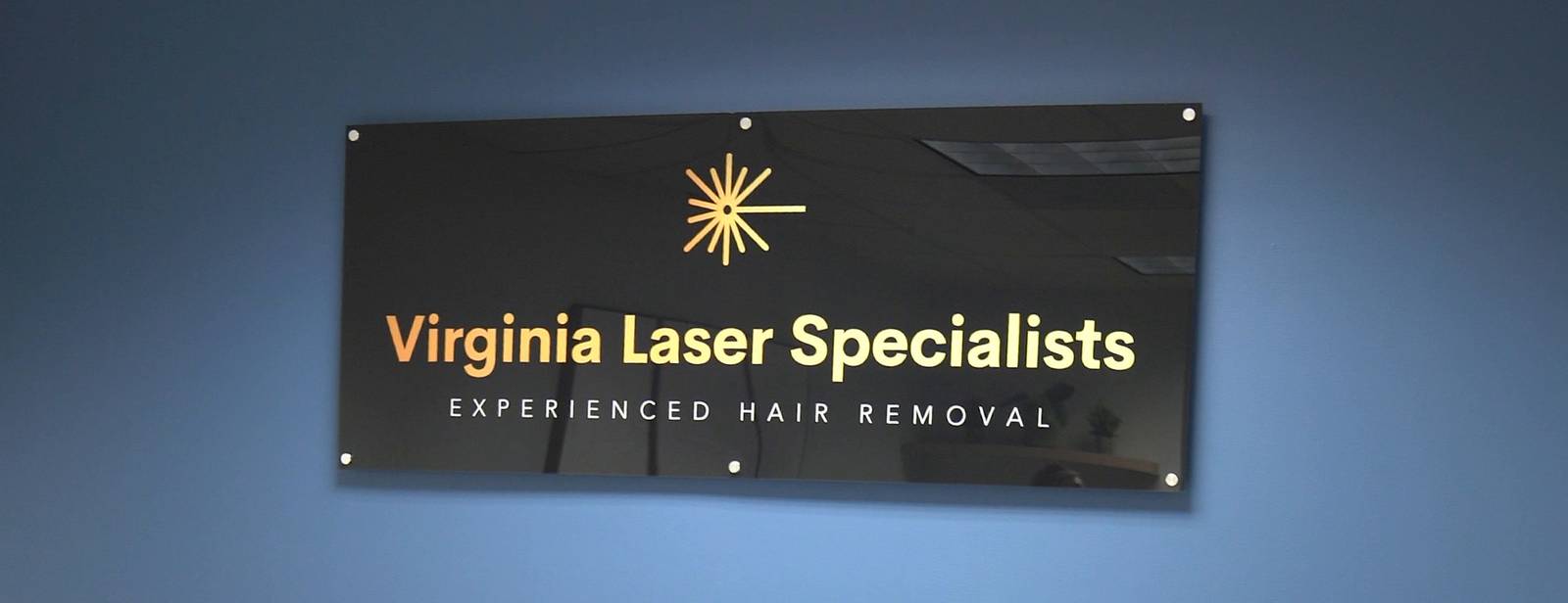 The Virginia Laser Specialists sign on the navy wall behind the reception desk